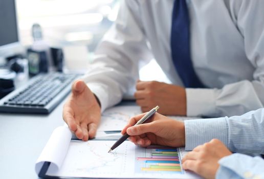 Unrecognizable business person analyzing graphs and taking notes