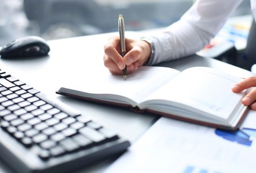 Businesswoman makes a note in notebook.