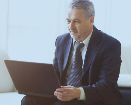 businessman in office with laptop sits and works