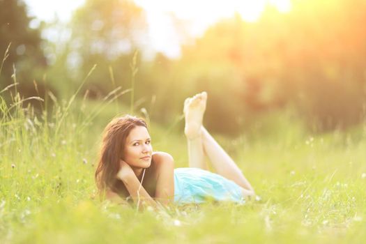 Beautiful young woman on grass in summer park on sunny day