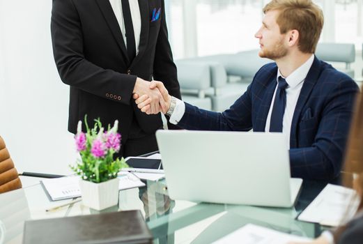 handshake between colleagues in the workplace in a modern office.the photo has a empty space for your text