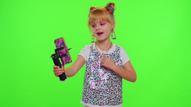 Stylish kid girl making trendy dance video for social media network, child dancing, blogger fun activity challenge, children hobbies games after school. Schoolgirl child on green chroma key background