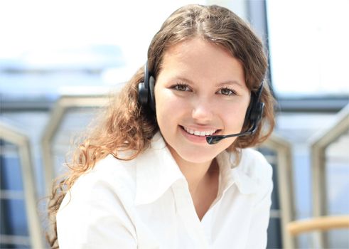 Beautiful young female call center operator with headset in office