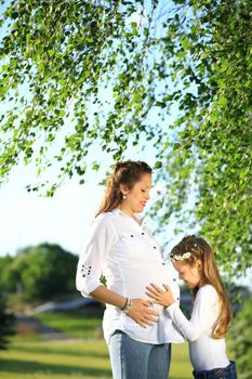 pregnant mother and little daughter on a walk in the Park on a Sunny day.