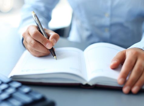 Businesswoman makes a note in notebook.