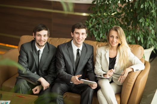 business team with tablet and documents in a work break, sitting on the couch in the lobby of the office