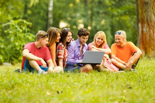 group of students with laptop relaxing in the Park on a Sunny
