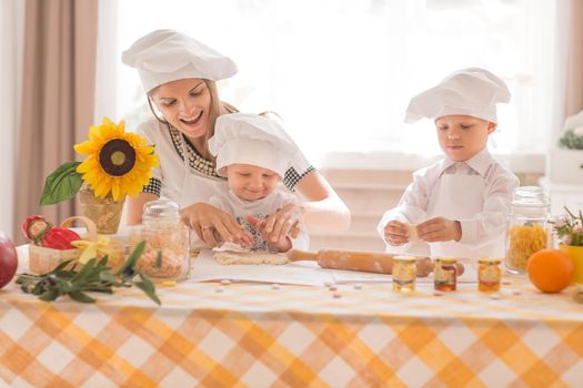 Happy mother and her child in the form of cooks prepare lunch, play with each other