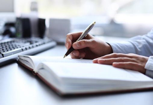 Businesswoman makes a note in notebook.