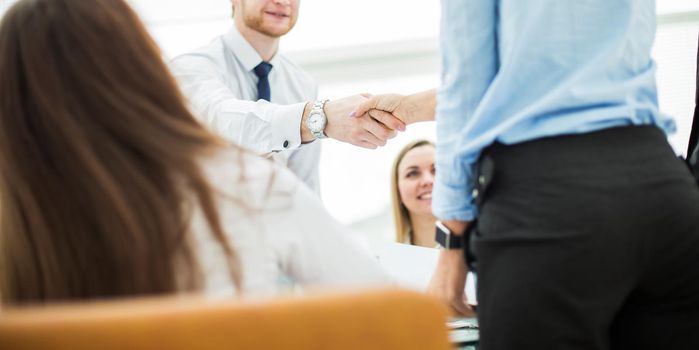 Bank Manager and the customer shake hands after signing a lucrative contract on the background of the modern office