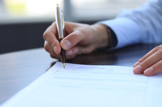 Businesswoman sitting at office desk signing a contract with shallow focus on signature.