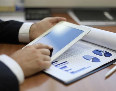 Image of human hand pointing at touchscreen in working environment at meeting