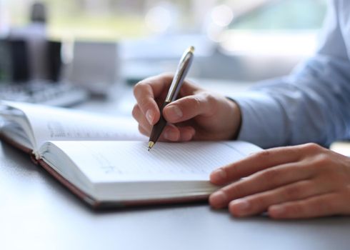 Businessman makes a note in notebook.