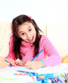 Beautiful girl draws with crayons and markers with surprise and joy on her face
