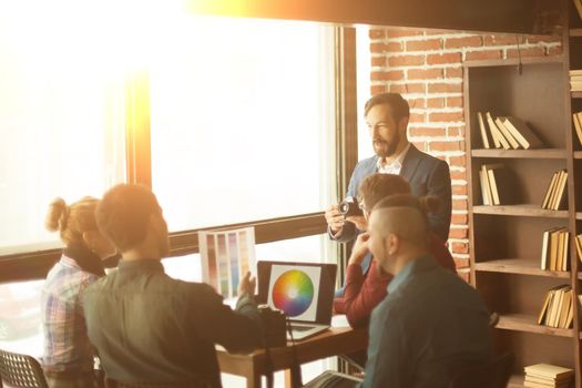 group of creative designers discussing a new color palette in the workplace in a modern office