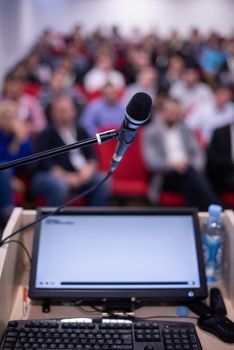 laptop computer and microphone at podium on business seminar education  in modern conference room