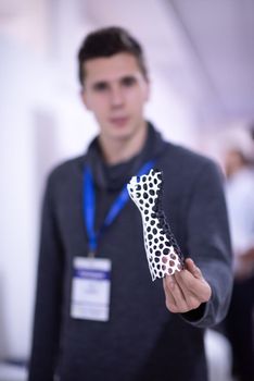 young engineer posing for the camera while showing a miniature model  having printed it with a 3D printer