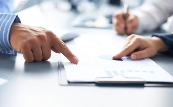 Unrecognizable business person analyzing graphs and taking notes