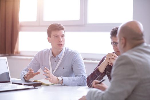 Group of a young business people brainstorming and discussing business plan on meeting at startup office interior