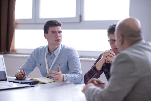 Group of a young business people brainstorming and discussing business plan on meeting at startup office interior