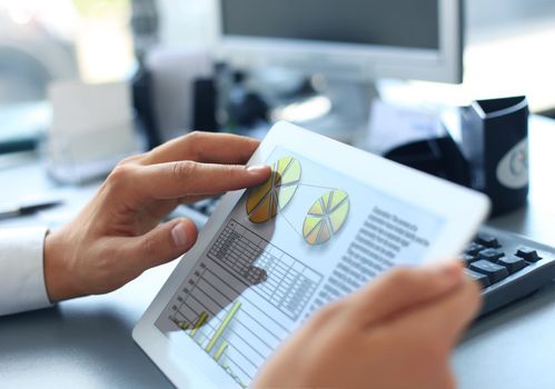 Business person analyzing financial statistics displayed on the tablet screen