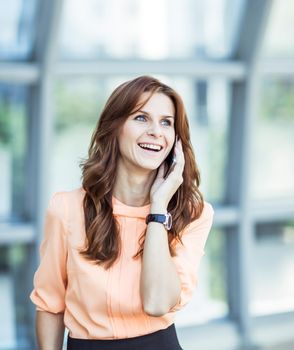 business woman talking on smartphone on background office.the photo has a empty space for your text