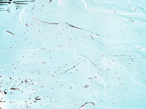 Liquid gel cosmetic texture on blue background. Aesthetic beautiful textured smears transparent skin gel. Top view or flat lay