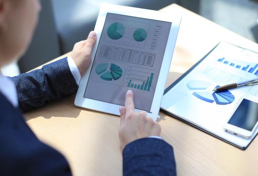 Business person analyzing financial statistics displayed on the tablet screen