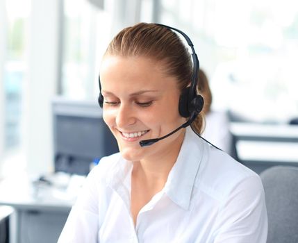 Beautiful young female call center operator with headset in office