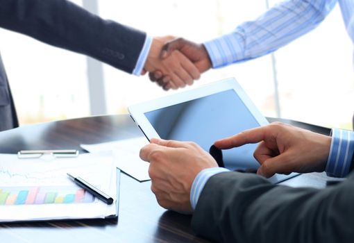 Business associates shaking hands in office