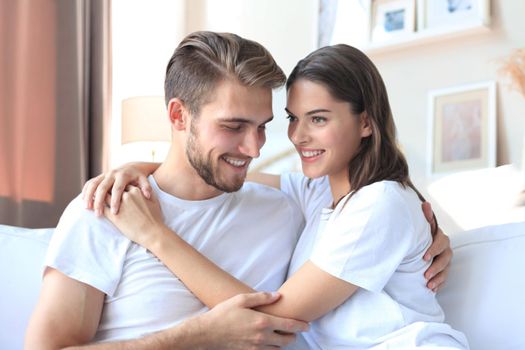 Happy young couple hugging and looking at each other at home interior