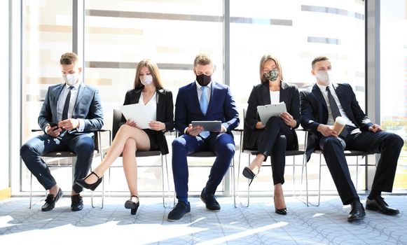 Stressful business people waiting for job interview with face mask, social distancing quarantine during COVID19 affect