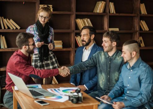 advertising Manager with a handshake greets the customer in a modern office