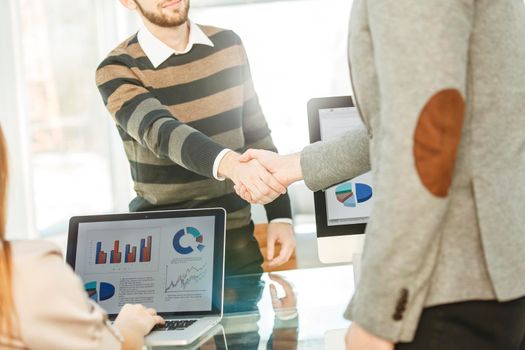 handshake between the client and the Manager of the company near the workplace in the modern office.