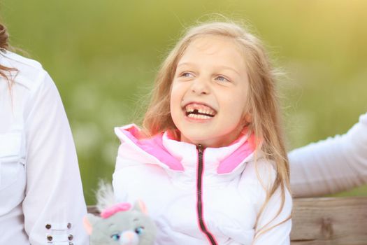 little girl with soft toy sitting with your parents on a Park bench on a Sunny day