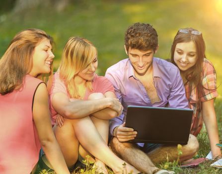 a group of students with laptop relaxing in the Park on a Sunny day