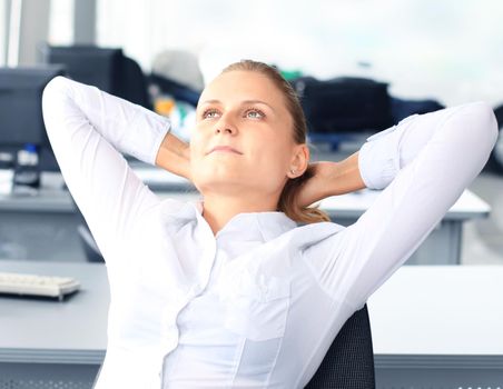 Business woman is relaxing with her hands behind her head and sitting on a chair in office