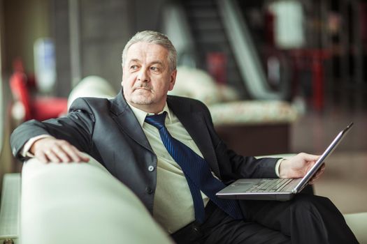 businessman working on laptop sitting on a white sofa in a private office