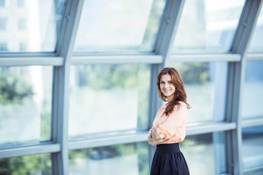 successful business woman near a large window in a modern office. the photo has a empty space for your text