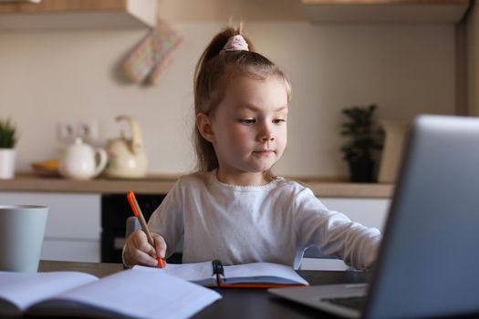 Serious little girl handwrite study online using laptop at home, cute happy small child take Internet web lesson or class on computer, homeschooling concept