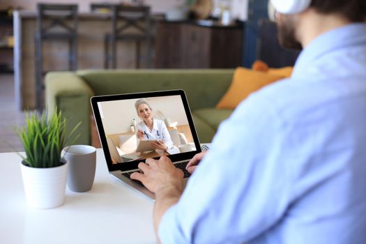 Man making video call with her doctor during self isolation and quarantine. Online consultation. Patient in video conferencing with general practitioner on digital laptop. Coronavirus