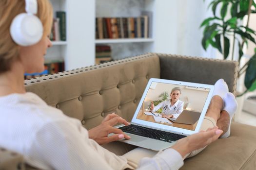 Middle aged woman making video call with her doctor during self isolation and quarantine. Online consultation. Patient in video conferencing with general practitioner on laptop