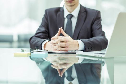 close-up of a successful businessman sitting behind a Desk, hands folded in front of him