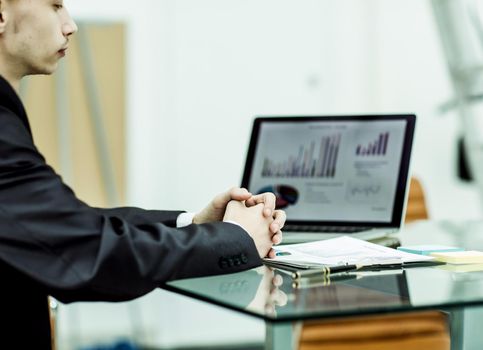 closeup of a Manager of the company sitting in front of the open laptop and working with financial information