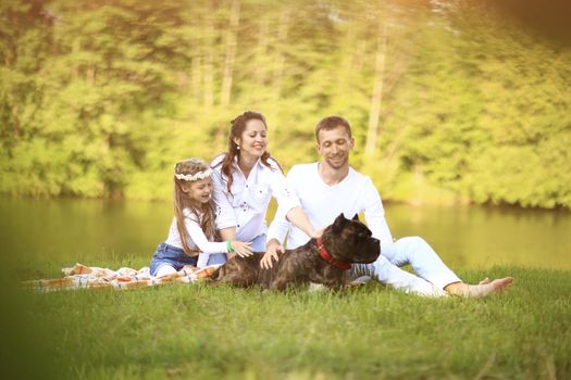 ,little daughter and their dog on a picnic by the river.the photo has a space for your text