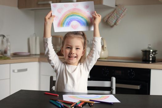 Girl painting rainbow at home, a symbol of UK National Health Service (NHS). Thanks to the doctors for their work. Stay at home Social media campaign