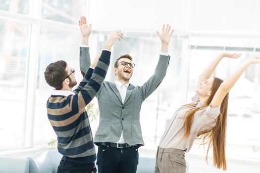 jubilant business team standing in a circle, hands up in rejoice success.the photo has a empty space for your text.