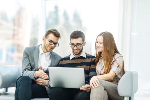 employees with a laptop sitting in the lobby of the office.the photo has a empty space for your text.