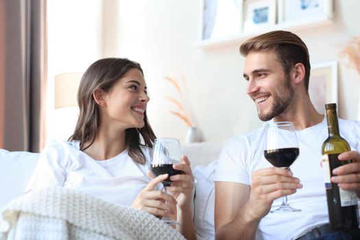 Young loving couple drinking a glass of red wine in their living room