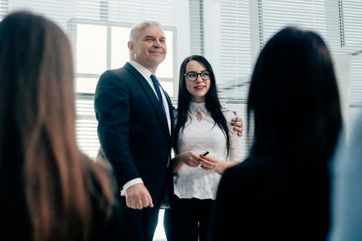 boss and young speaker standing together in front of business presentation listeners . success concept